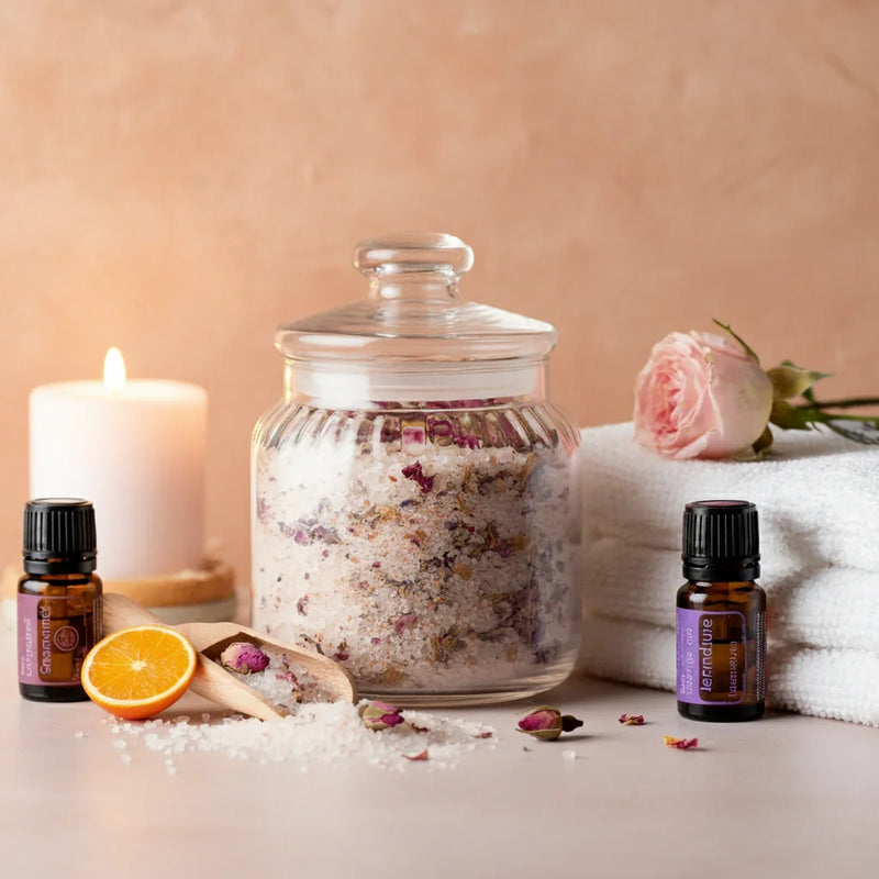 glass jar with bath salts next to towel, candle, and essential oils